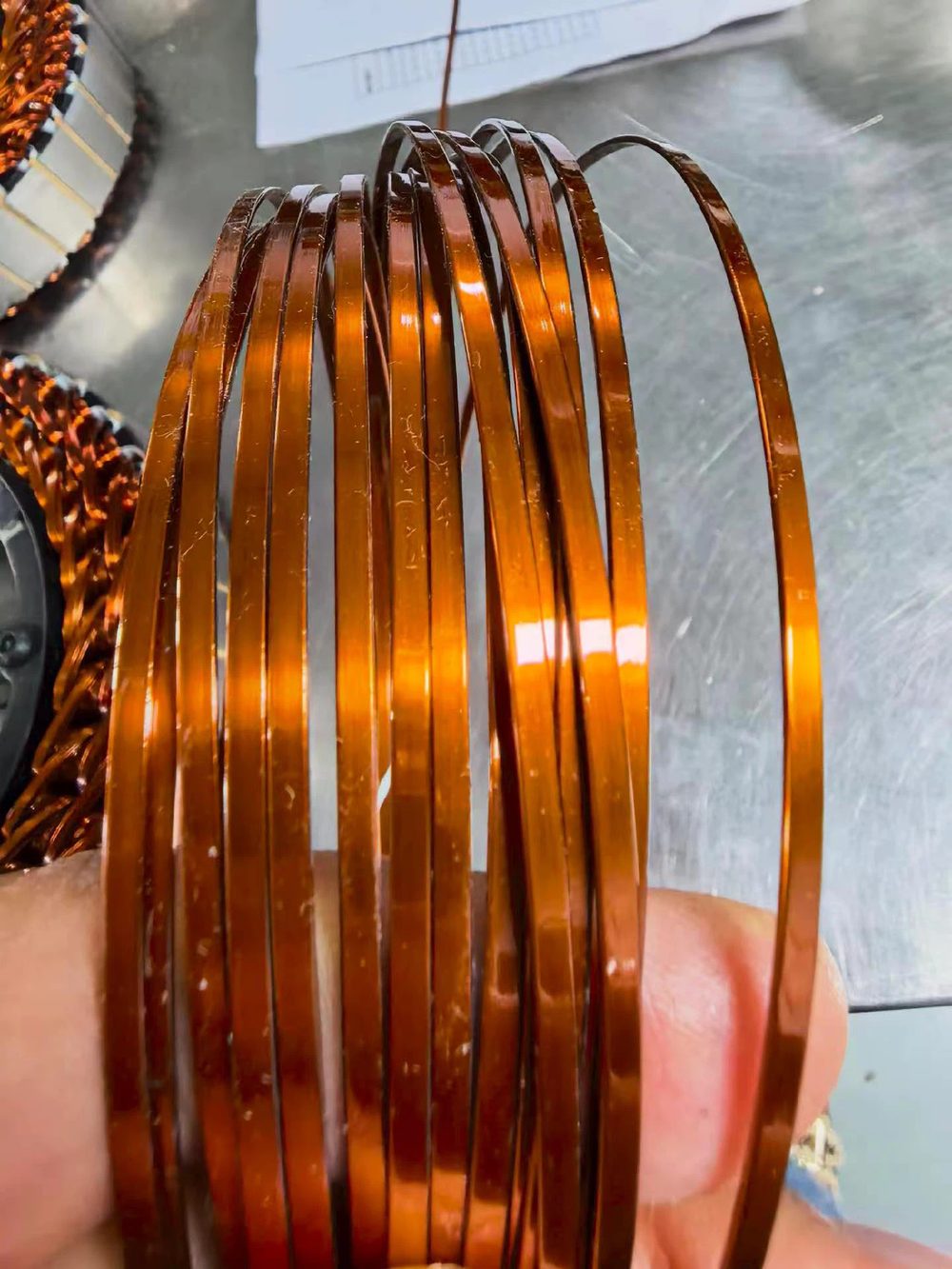 Hand holding flat enamelled copper coil turns