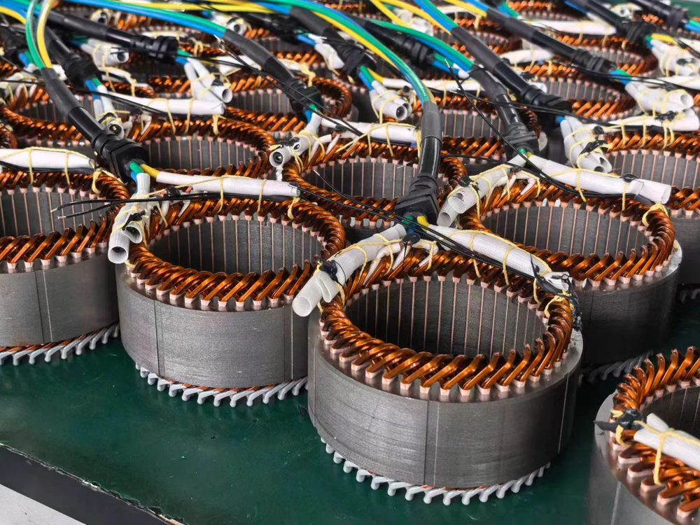 Multiple wound stators lined up on a green workbench